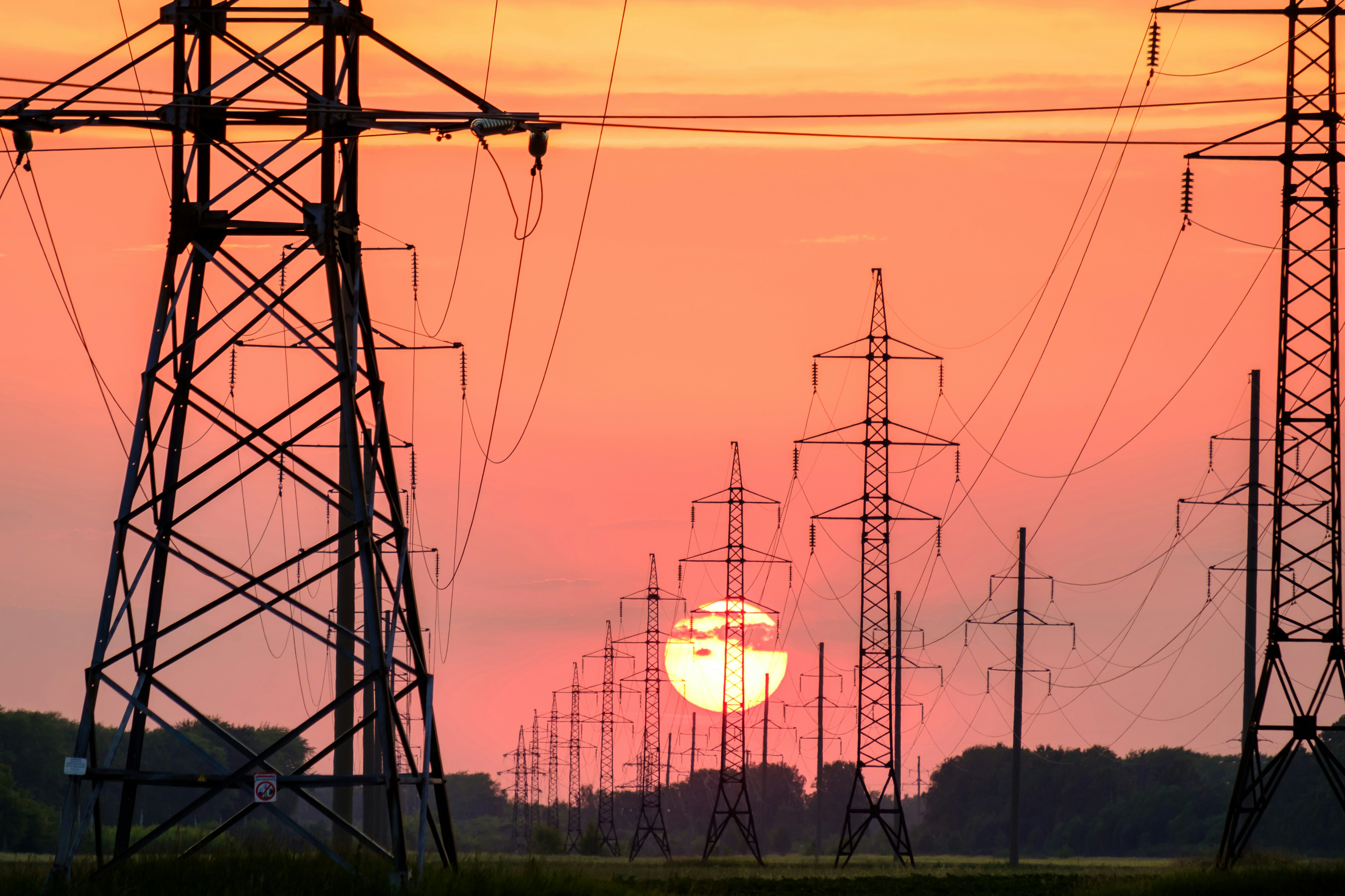 Strommasten als Silhouette vor rotem Sonnenuntergang