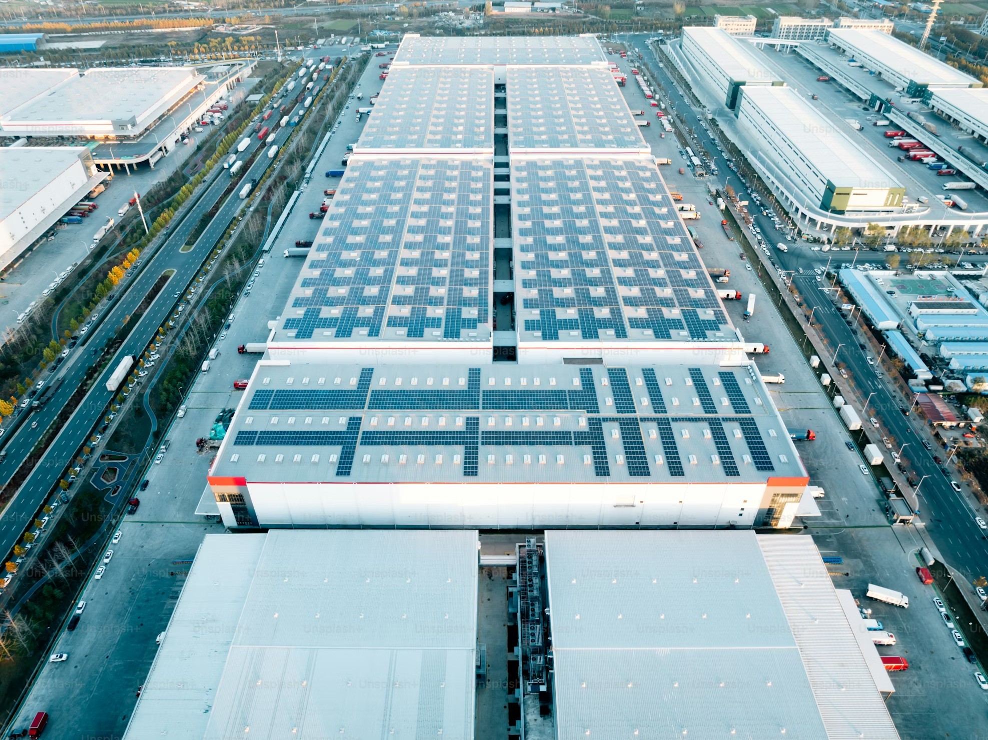 Aerial view of large industrial halls with partial photovoltaic coverage on the roofs