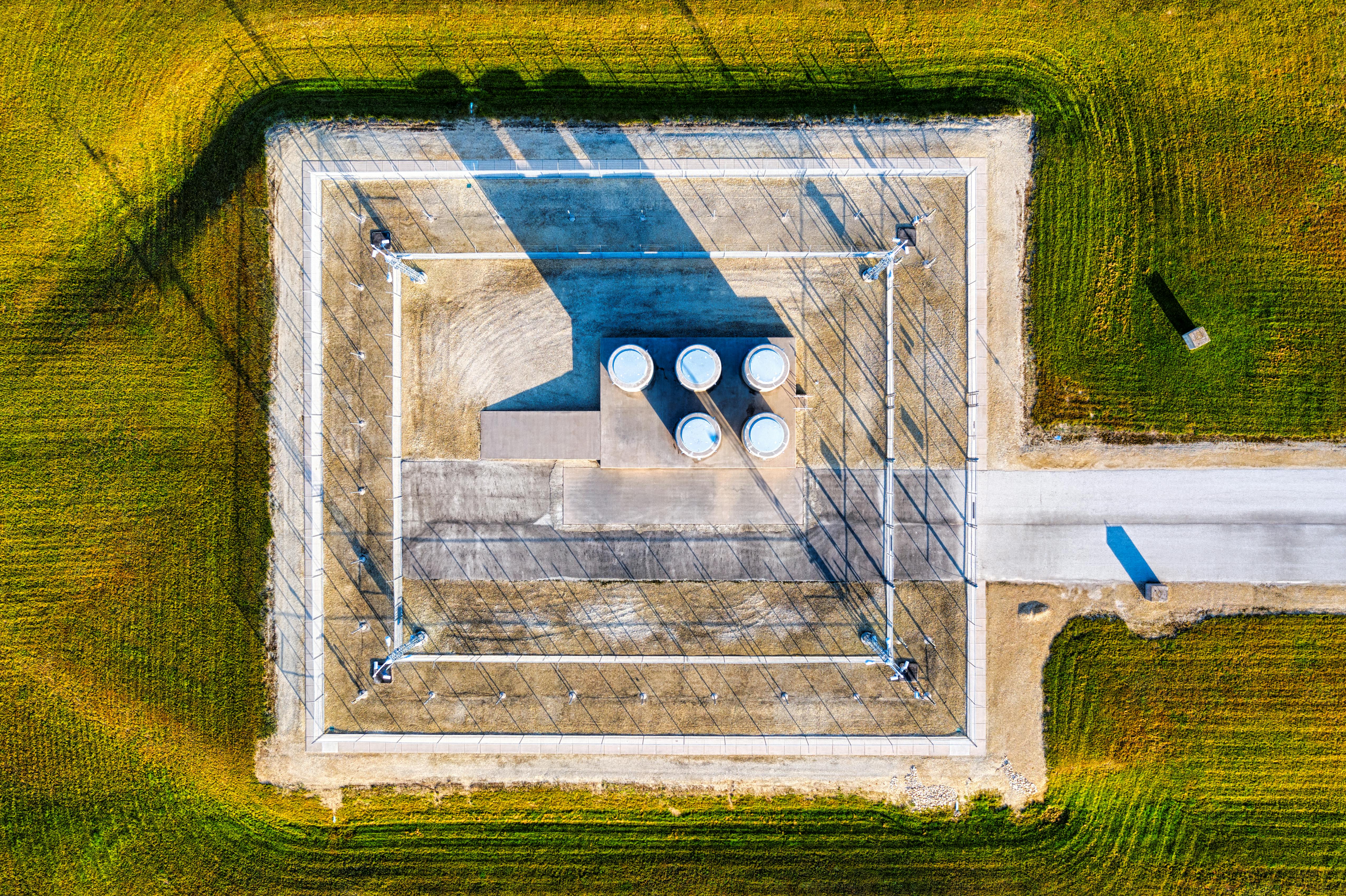 Aerial view of a substation with four containers, surrounded by green fields