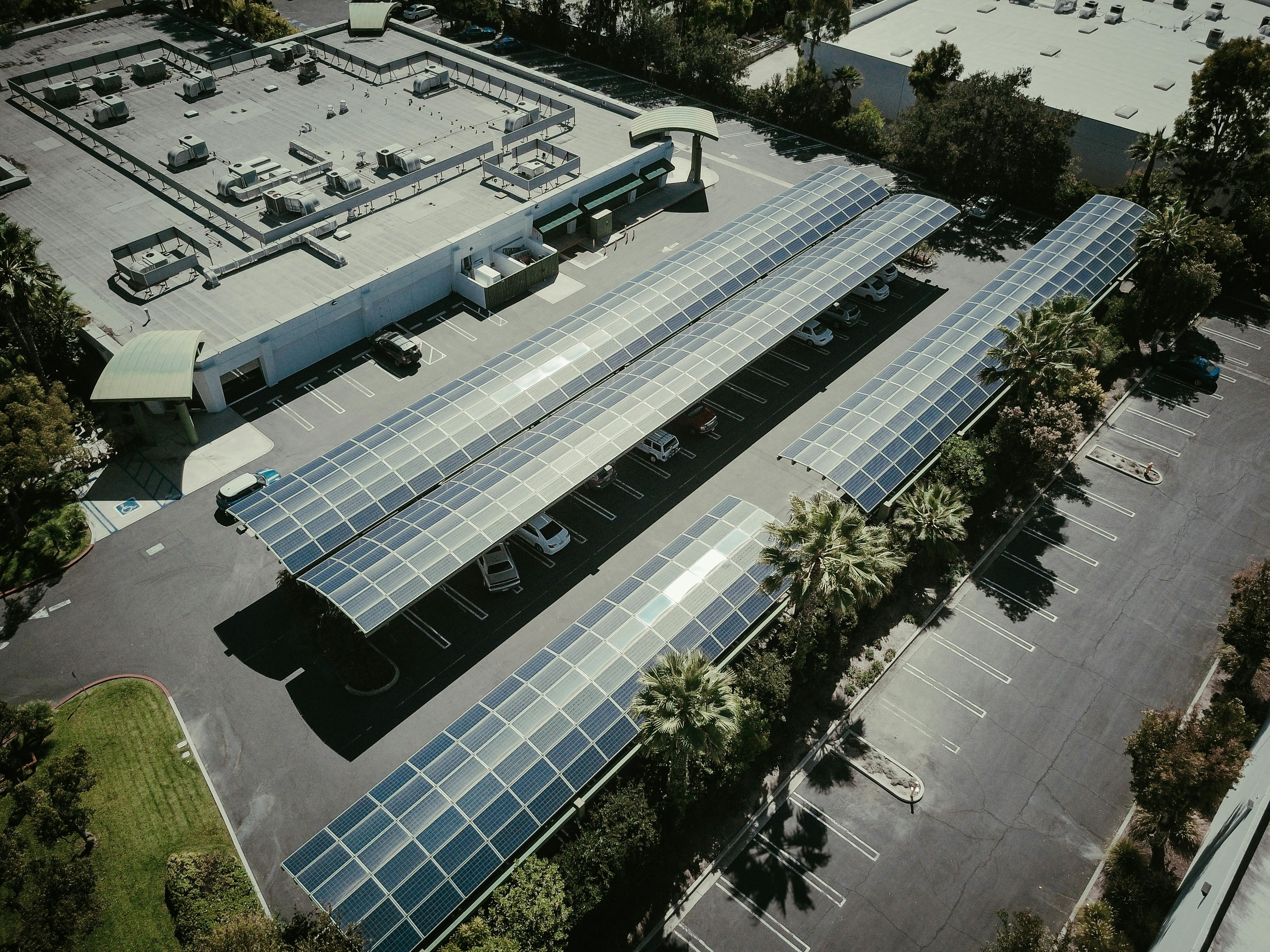 Aerial view of a commercial building with solar carports and photovoltaic modules over parking lots